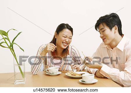 Close-up of a young couple looking at a cookie and smiling View Large Photo Image Stock Image - Close-up of a young couple looking at a cookie and smiling. Fotosearch