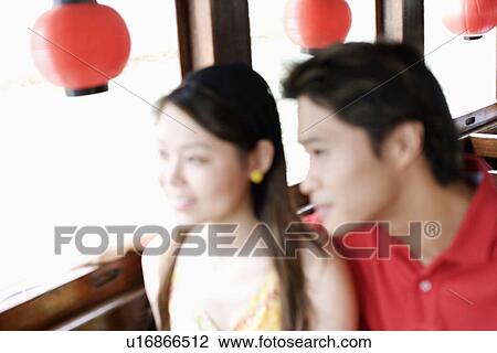 Stock Image - Close-up of a young couple looking outside the window of a tourboat. Fotosearch