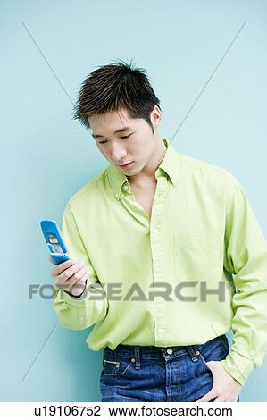 Stock Image - Close-up of a young man looking at a mobile phone. Fotosearch