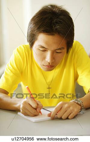 Stock Photograph - Close-up of a young man writing on a notepad. Fotosearch