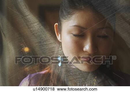 Stock Photo - Close-up of a young woman behind a curtain. Fotosearch
