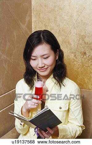 Stock Photo - Close-up of a young woman holding a glass and a greeting card. Fotosearch