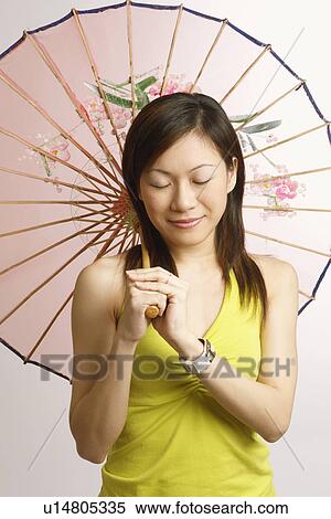 Stock Photography - Close-up of a young woman holding a parasol and smiling. Fotosearch