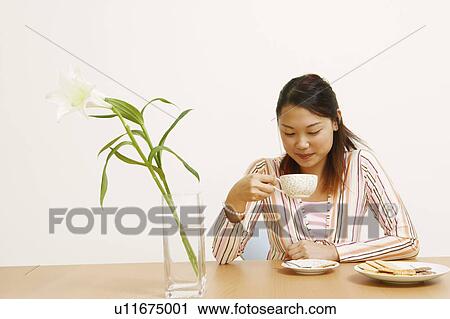 Stock Image - Close-up of a young woman holding a tea cup and smiling. Fotosearch