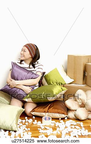 Close-up of a young woman hugging a cushion and smiling View Large Photo Image Stock Photography - Close-up of a young woman hugging a cushion and smiling. Fotosearch