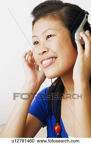 Close-up of a young woman listening to music and smiling View Large Photo Image Stock Image - Close-up of a young woman listening to music and smiling. Fotosearch