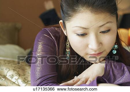 Stock Photograph - Close-up of a young woman lying down thinking. Fotosearch