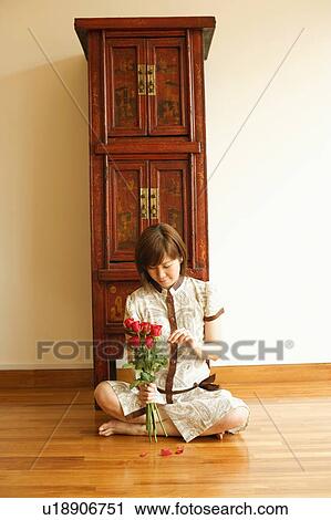 Close-up of a young woman sitting on the floor and plucking a rose View Large Photo Image Stock Image - Close-up of a young woman sitting on the floor and plucking a rose. Fotosearch
