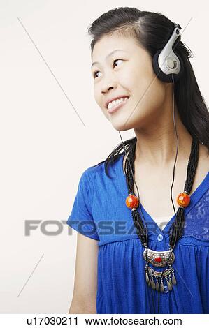 Stock Image - Close-up of a young woman wearing headphones and listening to music. Fotosearch