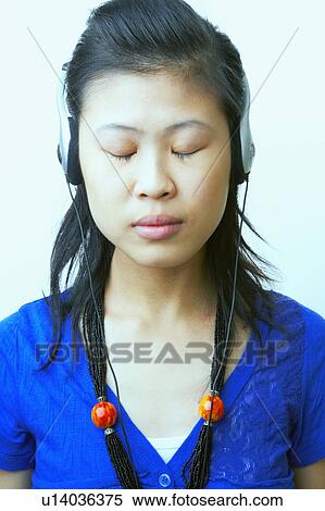 Stock Photography - Close-up of a young woman wearing headphones and listening to music. Fotosearch