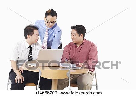 Stock Photo - Close-up of three businessmen discussing in front of a laptop. Fotosearch