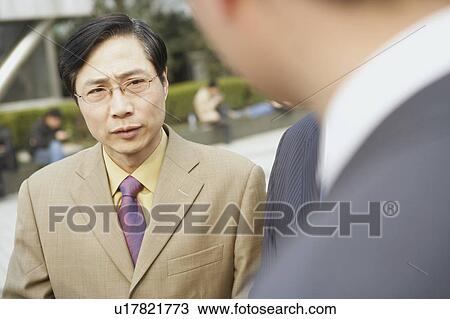 Stock Image - Close-up of two businessmen standing face to face. Fotosearch
