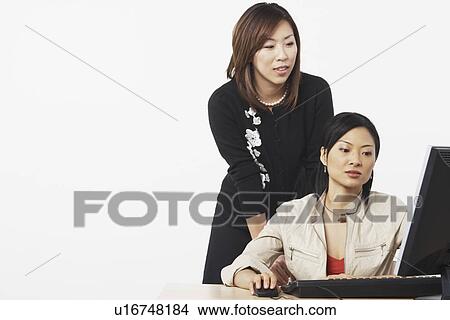 Close-up of two businesswomen using a computer View Large Photo Image Picture - Close-up of two businesswomen using a computer. Fotosearch