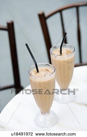 Stock Image - Close-up of two glasses of milkshake on the table. Fotosearch