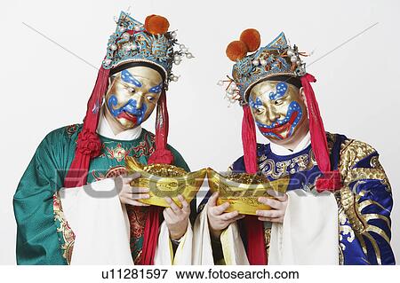 Stock Photo - Close-up of two male Chinese opera performers looking at bowls full of gold coins. Fotosearch