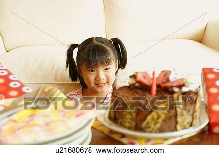 Stock Photo - Girl smiling and looking at a cake. Fotosearch
