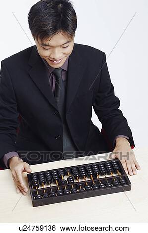 Stock Photograph - High angle view of a businessman looking at an abacus and smiling. Fotosearch