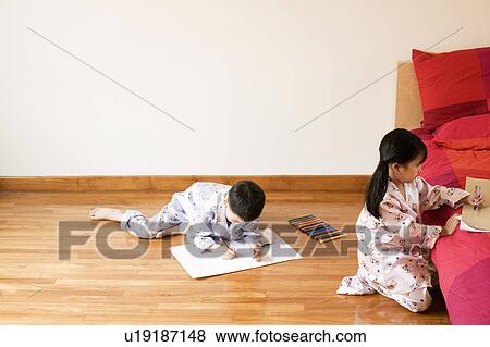 Stock Photo - High angle view of a girl and boy drawing on paper. Fotosearch