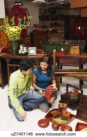 High angle view of a young man and a young couple choosing merchandise in a store View Large Photo Image Stock Photograph - High angle view of a young man and a young couple choosing merchandise in a store. Fotosearch