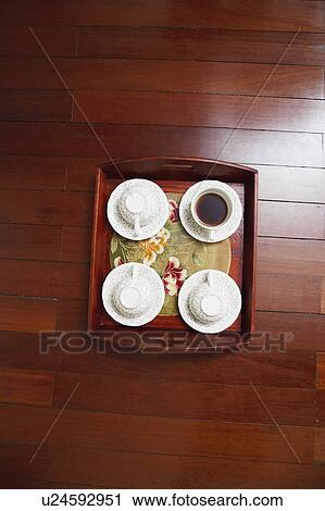 Stock Image - High angle view of tea cups with a tray on a hardwood floor. Fotosearch