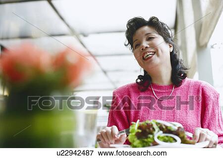 Low angle view of a mature woman seated at the table in a restaurant smiling View Large Photo Image Stock Photo - Low angle view of a mature woman seated at the table in a restaurant smiling. Fotosearch