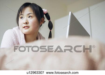 Stock Photo - Low angle view of a young woman sitting in front of a laptop. Fotosearch