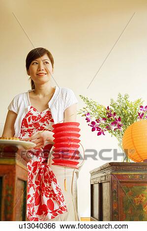 Low angle view of a young woman sitting on a couch and holding a Chinese lantern View Large Photo Image Stock Photograph - Low angle view of a young woman sitting on a couch and holding a Chinese lantern. Fotosearch