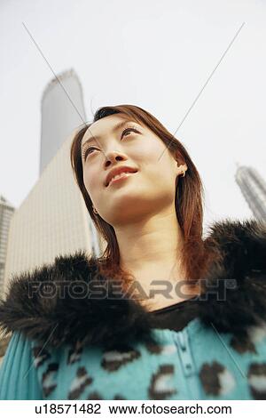 Stock Image - Low angle view of a young woman smiling. Fotosearch
