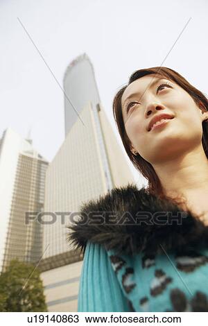 Stock Image - Low angle view of a young woman smiling. Fotosearch