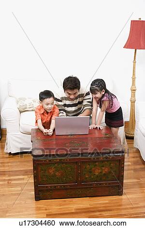 Mid adult man using a laptop with his son and daughter beside him View Large Photo Image Stock Image - Mid adult man using a laptop with his son and daughter beside him. Fotosearch