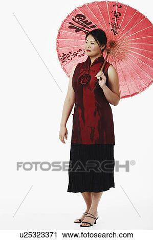 Stock Image - Mid adult woman holding a parasol. Fotosearch