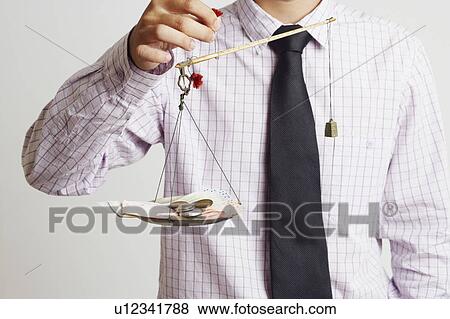 Mid section view of a businessman weighing paper currency with coins on a weighing scale View Large Photo Image Stock Photo - Mid section view of a businessman weighing paper currency with coins on a weighing scale. Fotosearch