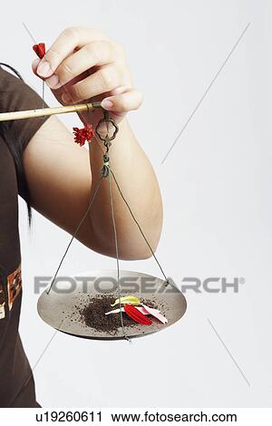 Stock Image - Mid section view of a mid adult woman holding petals on a weight scale. Fotosearch