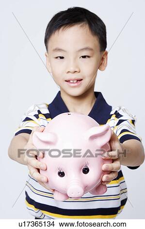 Picture - Portrait of a boy holding a piggy bank. Fotosearch
