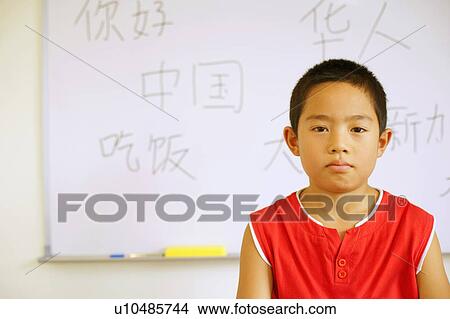 Picture - Portrait of a boy in front of a whiteboard in the classroom. Fotosearch