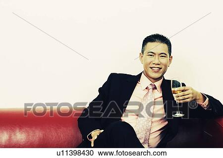 Portrait of a businessman holding a champagne flute and smiling View Large Photo Image Stock Image - Portrait of a businessman holding a champagne flute and smiling. Fotosearch
