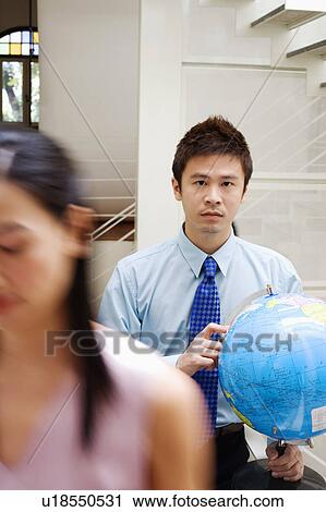 Stock Image - Portrait of a businessman holding a globe. Fotosearch