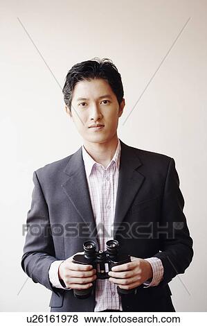 Stock Photo - Portrait of a businessman holding a pair of binoculars. Fotosearch