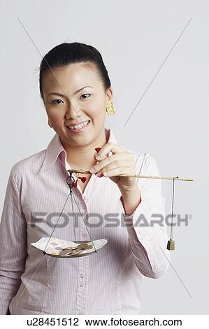 Portrait of a businesswoman weighing paper currency with coins on a weighing scale and smiling View Large Photo Image Stock Image - Portrait of a businesswoman weighing paper currency with coins on a weighing scale and smiling. Fotosearch
