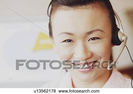 Portrait of a female customer service representative talking on a headset and smiling View Large Photo Image Stock Photo - Portrait of a female customer service representative talking on a headset and smiling. Fotosearch
