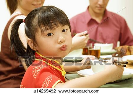 Stock Image - Portrait of a girl eating with chopsticks. Fotosearch