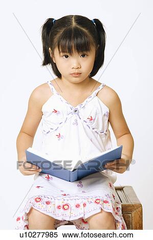 Stock Photography - Portrait of a girl holding a book and sitting on a stool. Fotosearch