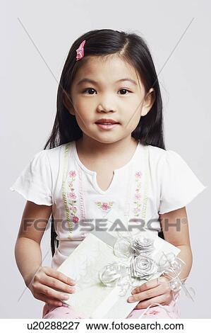 Portrait of a girl holding a gift and smiling View Large Photo Image Stock Photo - Portrait of a girl holding a gift and smiling. Fotosearch
