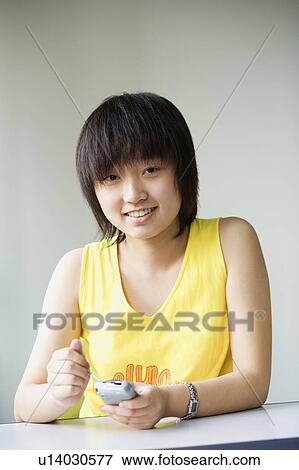 Stock Photo - Portrait of a girl holding a mobile phone. Fotosearch