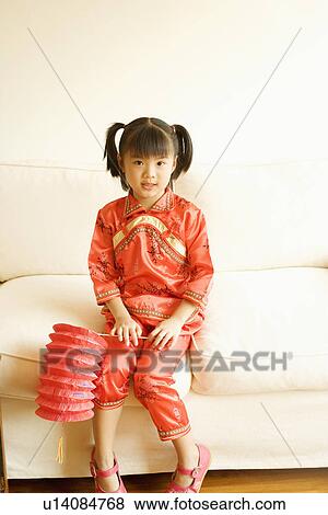 Stock Photo - Portrait of a girl sitting on a couch and holding a Chinese lantern. Fotosearch