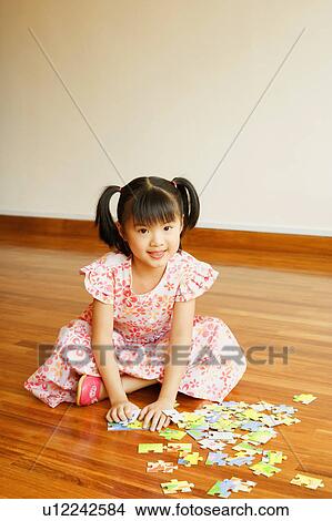Portrait of a girl smiling and playing with a jigsaw puzzle View Large Photo Image Picture - Portrait of a girl smiling and playing with a jigsaw puzzle. Fotosearch