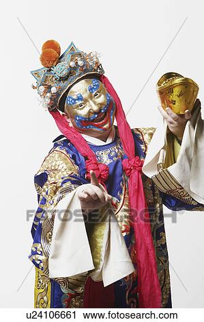 Stock Image - Portrait of a male Chinese opera performer holding a bowl full of gold coins. Fotosearch