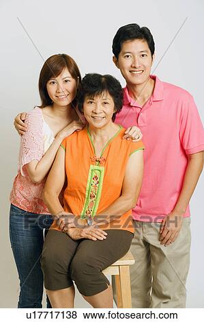 Portrait of a mature woman sitting on a stool and a young couple standing beside her View Large Photo Image Stock Photo - Portrait of a mature woman sitting on a stool and a young couple standing beside her. Fotosearch