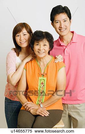 Portrait of a mature woman sitting on a stool with a young couple standing beside her View Large Photo Image Stock Photography - Portrait of a mature woman sitting on a stool with a young couple standing beside her. Fotosearch
