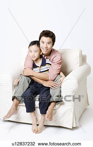 Stock Image - Portrait of a mid adult man hugging his son from behind. Fotosearch